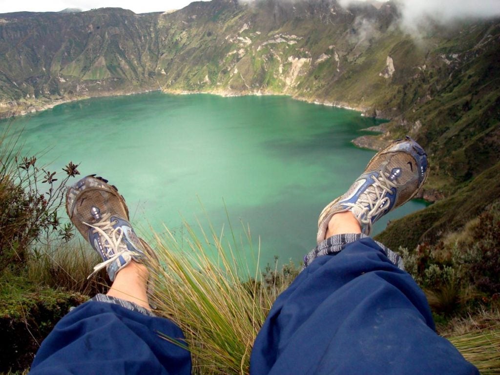 Feet hanging over a cliff over water