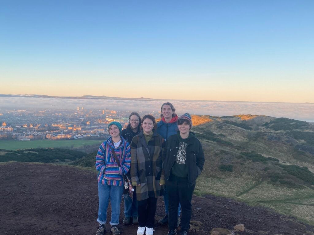 Nell standing with four members of her theater family on the climb up the hill Arthur's Seat, Edinburgh clearly visible behind them.