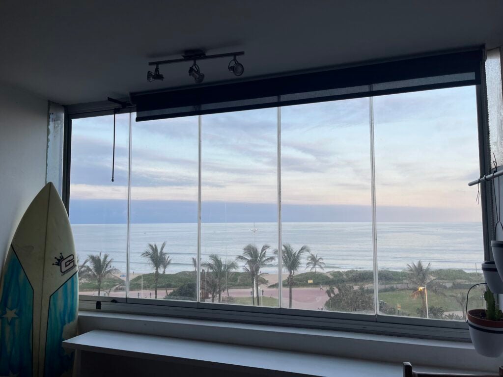 View of ocean from apartment with surfboard