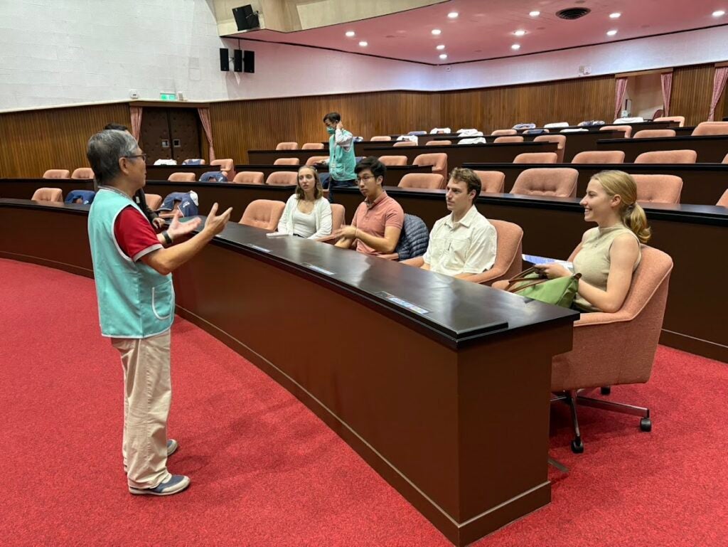 A seminar room with 4 people listening to an individual explain