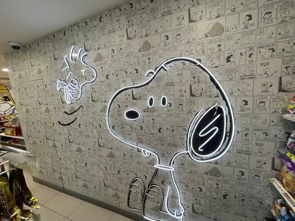 An LED sign of Snoopy and Woodstock along a comic strip wallpaper wall