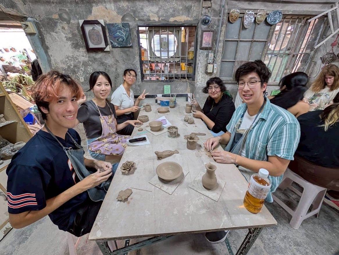 Group of people doing pottery around a table
