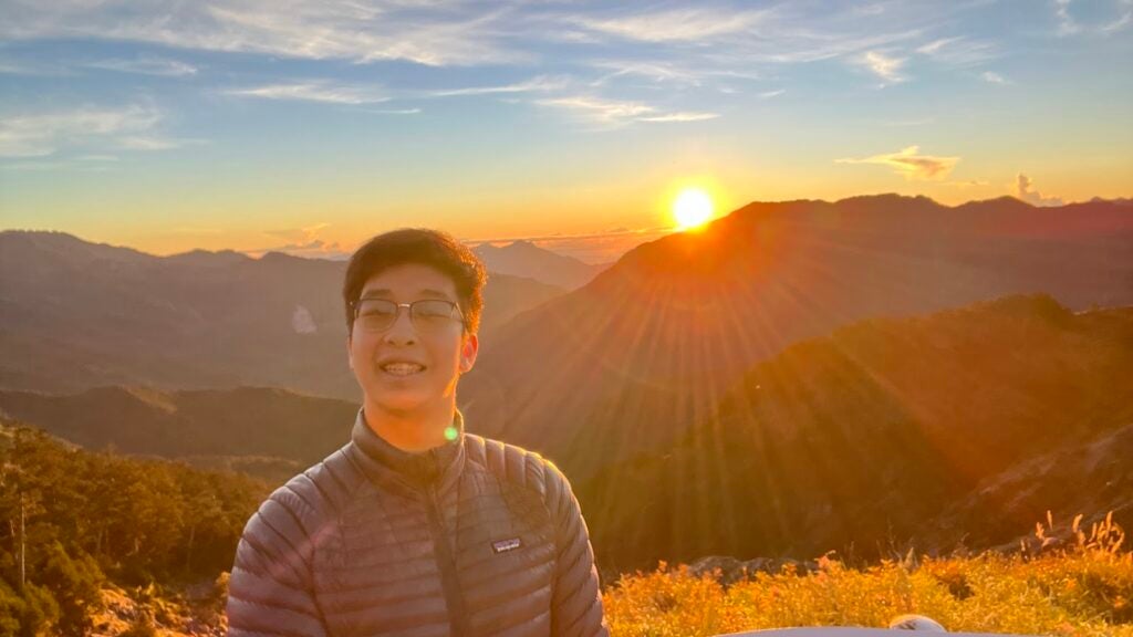 Jonathan above a sea of clouds with a sunrise behind him