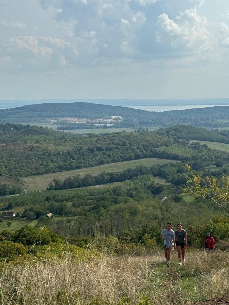 3 people walking up a hill towards the photographer, surrounded by greenery