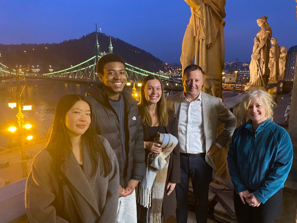 5 people posing by a bridge and sculptures